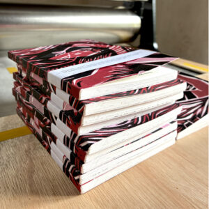livres à la couverture rouge et noir posés sur le plateau d'une presse